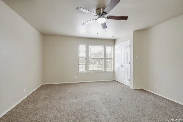 an empty room with a ceiling fan and windows