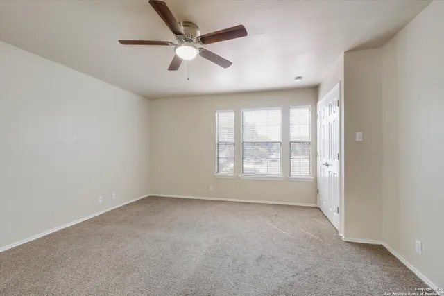an empty room with a ceiling fan and window