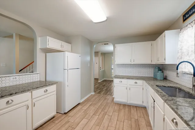 a kitchen with a sink a refrigerator and white cabinets