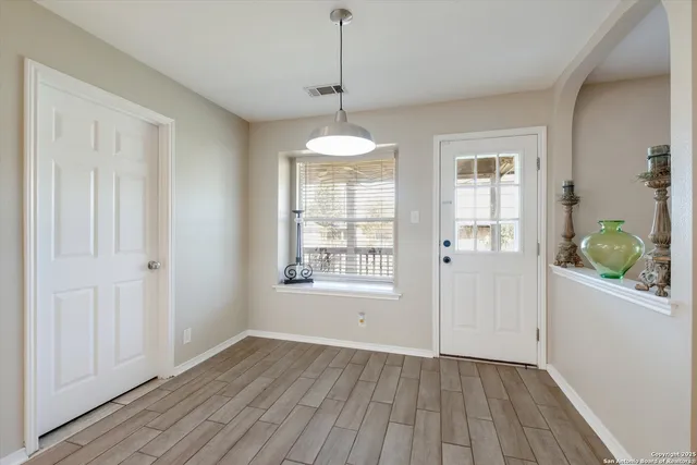 a view of an empty room with wooden floor and a window