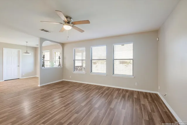 a view of an empty room with a window and wooden floor