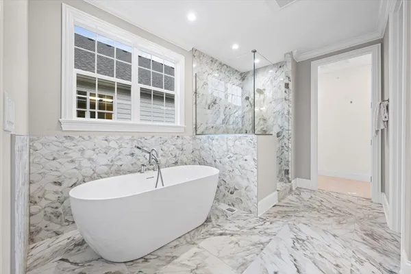 a white bath tub sitting in a bathroom next to a window