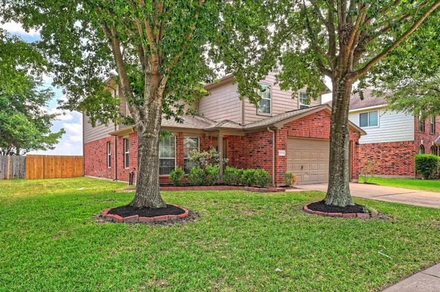 a front view of a house with garden and tree