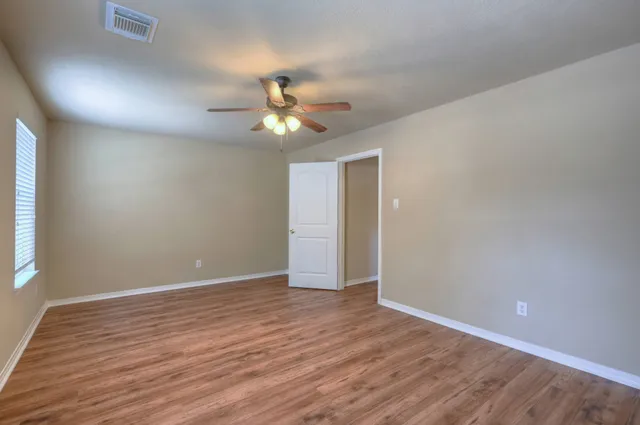 an empty room with wooden floor and windows