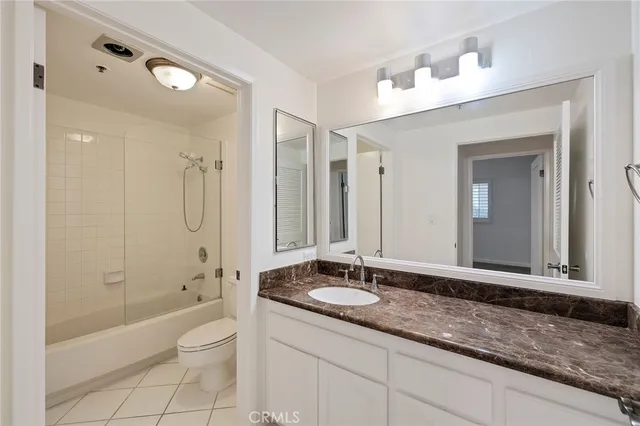 a bathroom with a granite countertop sink a toilet a mirror and bathtub