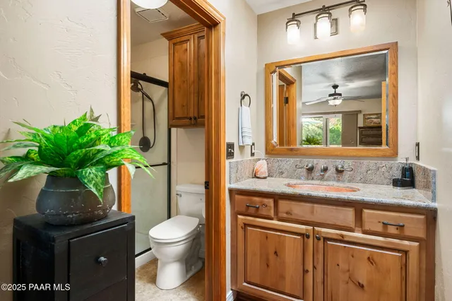 a bathroom with a granite countertop sink toilet and mirror