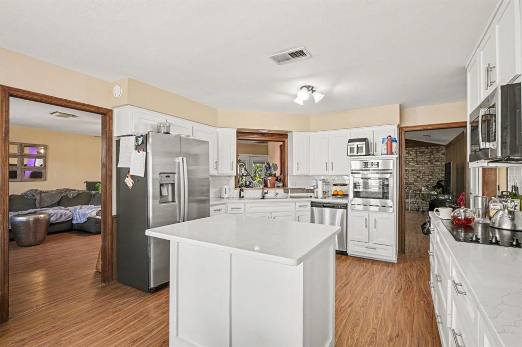 5009 River Ridge Road Arlington, TX 76017 - Photo 10 of 28 a kitchen with stainless steel appliances a refrigerator a stove top oven a wooden floor and cabinets