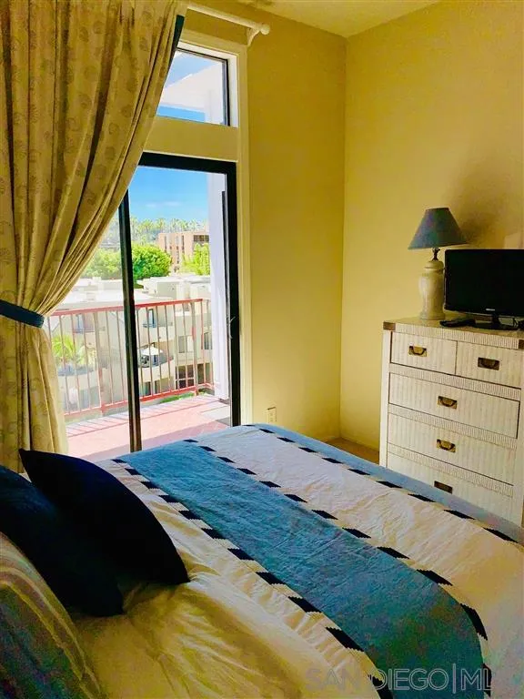 2130 Vallecitos, Unit 441 La Jolla, CA 92037 - Photo 16 of 25 a bedroom with a bed and a flat tv screen next to a window