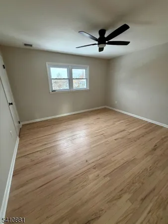an empty room with wooden floor fan and windows