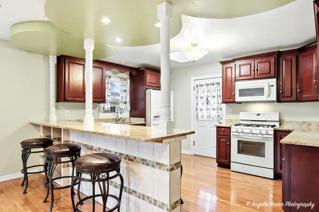 a kitchen with stainless steel appliances granite countertop a stove top oven a sink a dining table and chairs with wooden floor