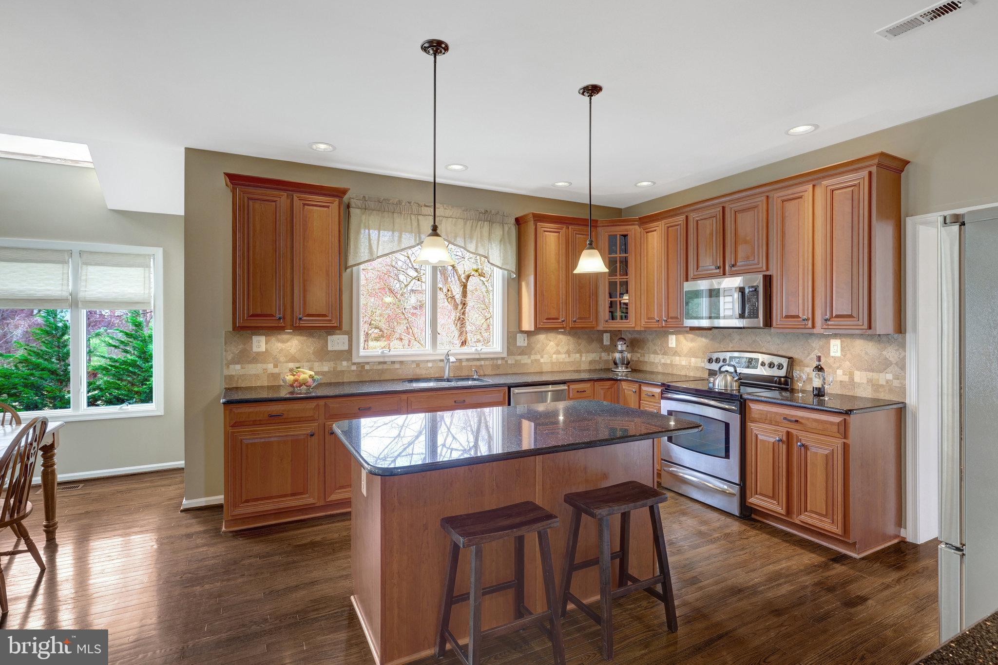12513 Ridgegate Drive Herndon, VA 20170 - Photo 17 of 72 a kitchen with stainless steel appliances granite countertop wooden floors stove and white cabinets