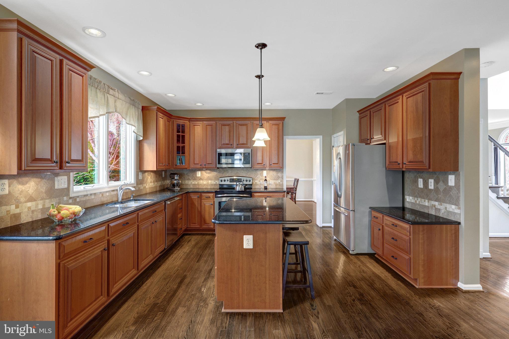 12513 Ridgegate Drive Herndon, VA 20170 - Photo 18 of 72 a kitchen with stainless steel appliances granite countertop a refrigerator a sink dishwasher a stove and white countertops with wooden floor