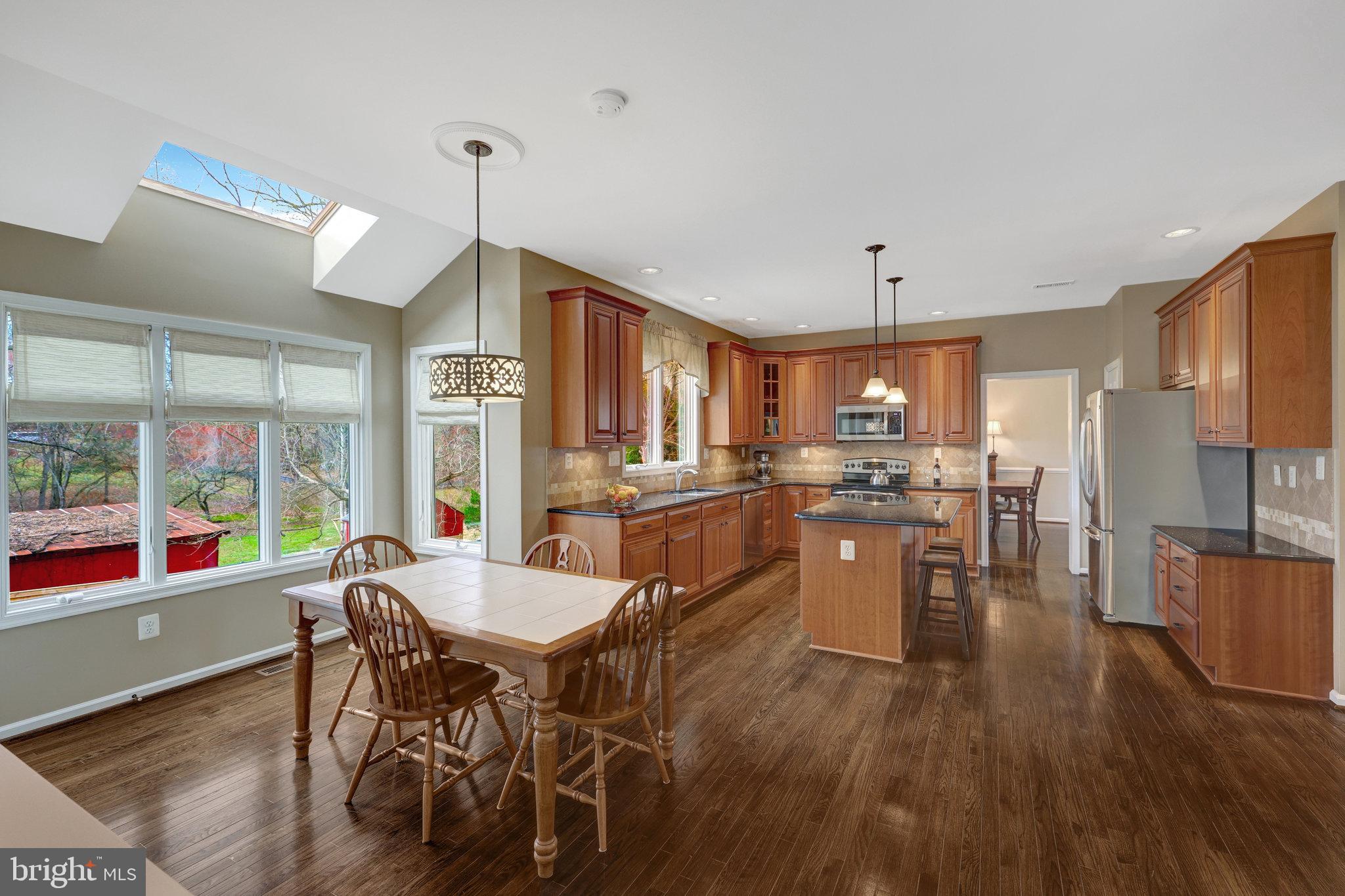 12513 Ridgegate Drive Herndon, VA 20170 - Photo 22 of 72 a kitchen with stainless steel appliances granite countertop a stove top oven a sink dishwasher a dining table and chairs with wooden floor