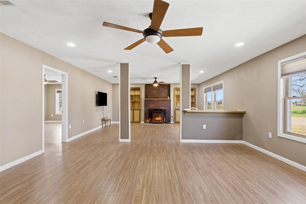 755 County Road 4280 Decatur, TX 76234 - Photo 8 of 36 a view of a big room with wooden floor a ceiling fan and windows