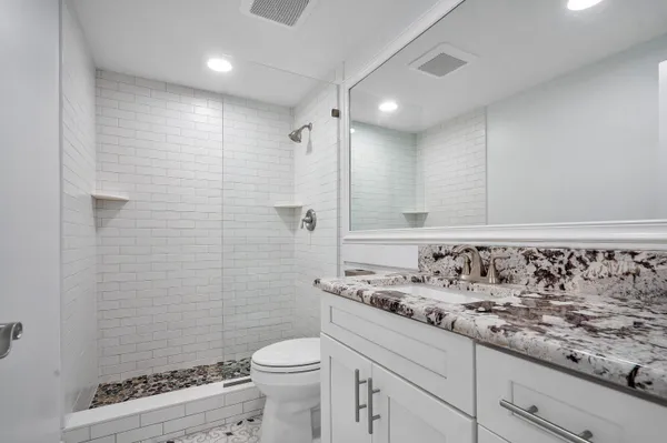 a bathroom with a granite countertop sink a toilet and shower