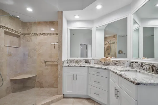 a bathroom with a granite countertop sink a toilet a mirror and shower
