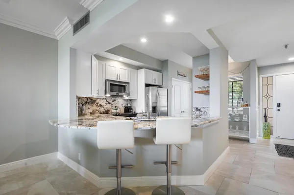 a kitchen with a dining table chairs cabinets and stainless steel appliances