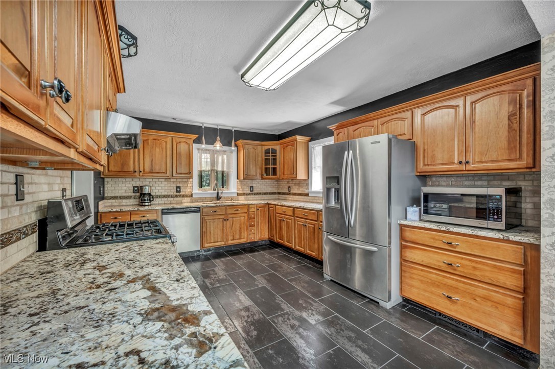 10982 Root Road Columbia Station, OH 44028 - Photo 5 of 49 Kitchen with appliances with stainless steel finishes, light stone counters, a textured ceiling, extractor fan, and glass insert cabinets