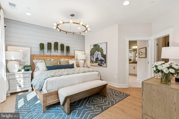 a bedroom with a large bed a chandelier and dresser
