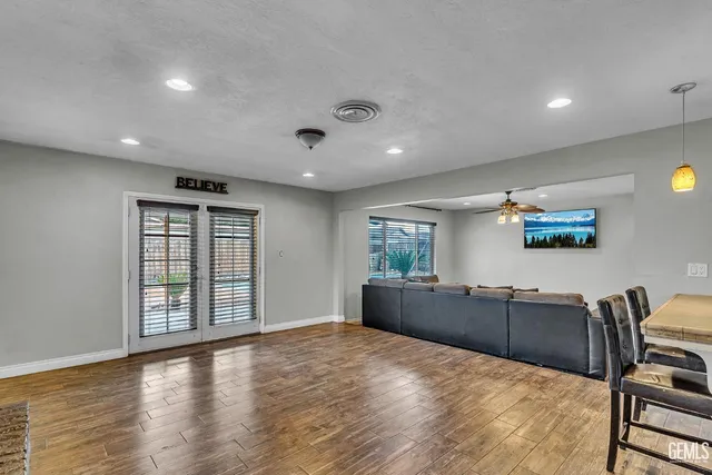 a large kitchen with kitchen island a large window wooden floor and stainless steel appliances