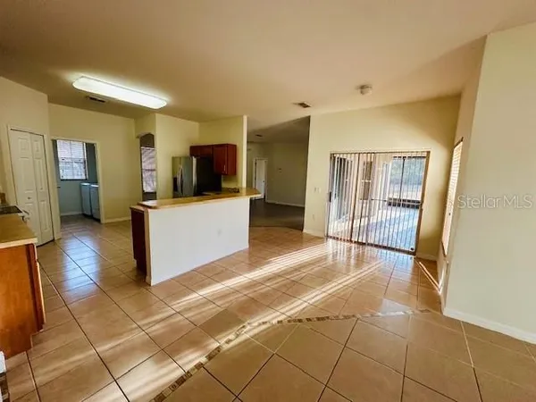 a view of a hallway with wooden floor and a kitchen