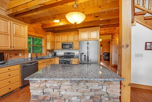 a kitchen with stainless steel appliances granite countertop a sink a stove cabinets counter space and a window