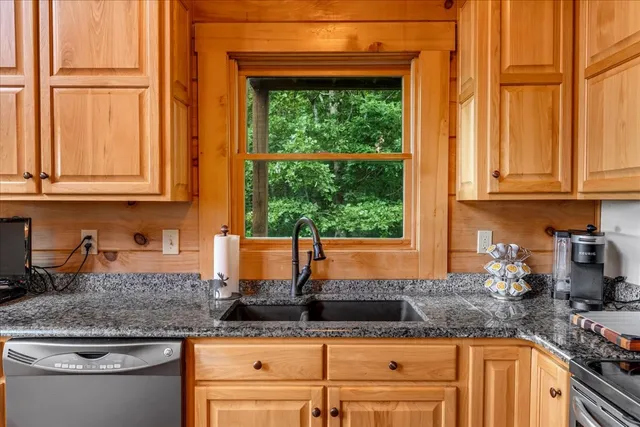 a kitchen with granite countertop a stove a sink and a wooden cabinets