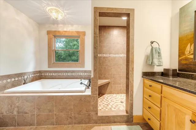 a bathroom with a granite countertop tub sink and mirror