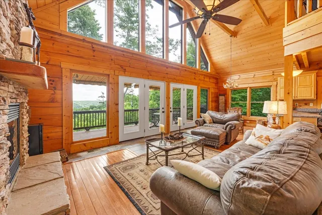 a living room with furniture floor to ceiling windows and wooden floor