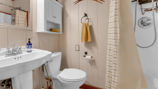 a bathroom with a sink a toilet and shower curtain