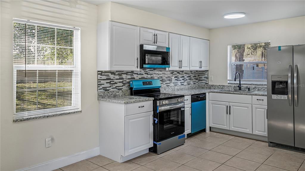 7906 Arabian Place Orlando, FL 32818 - Photo 4 of 23 a kitchen with stainless steel appliances granite countertop a stove a refrigerator and a microwave