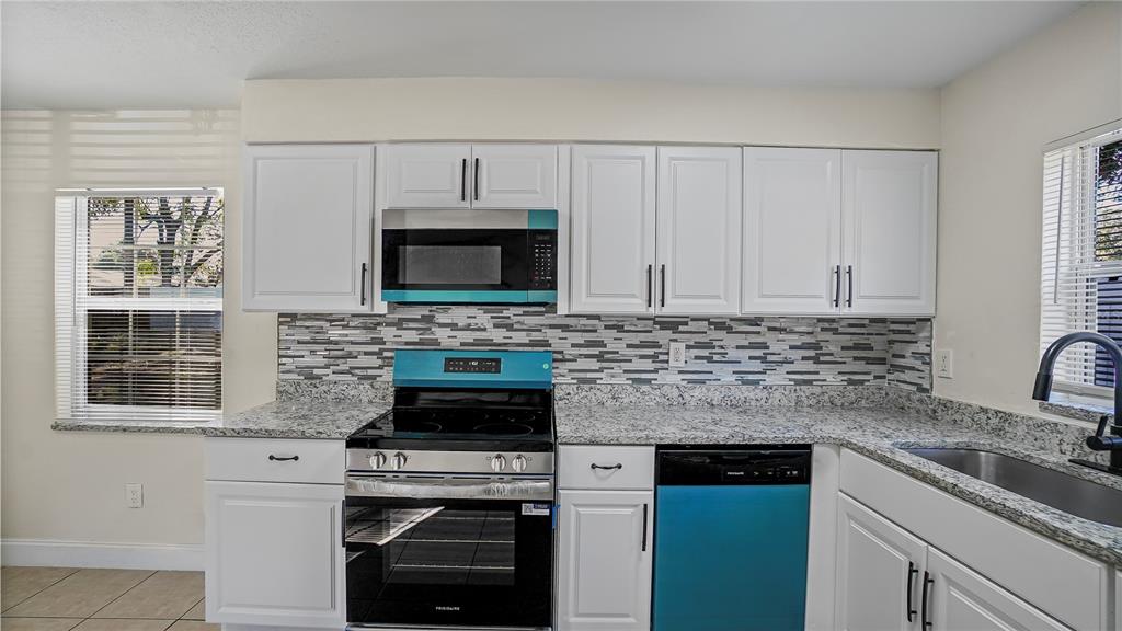 7906 Arabian Place Orlando, FL 32818 - Photo 5 of 23 a kitchen with granite countertop white cabinets and white appliances