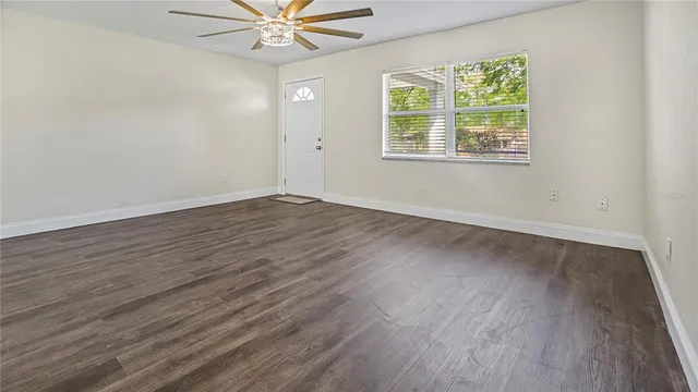 a view of an empty room with wooden floor and a window