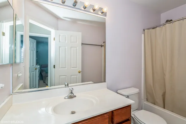 a bathroom with a sink a toilet a mirror and shower curtain