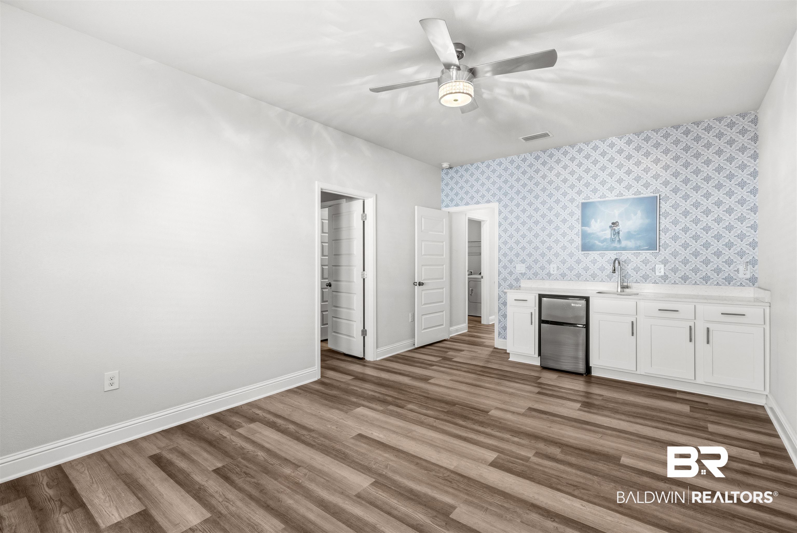 485 Shepard Street Gulf Shores, AL 36542 - Photo 26 of 53 In-Law Suite family room featuring white cabinetry an accent wall, and wet bar with refrigerator.