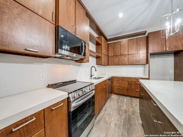 a kitchen with stainless steel appliances granite countertop a sink a stove and a wooden floors