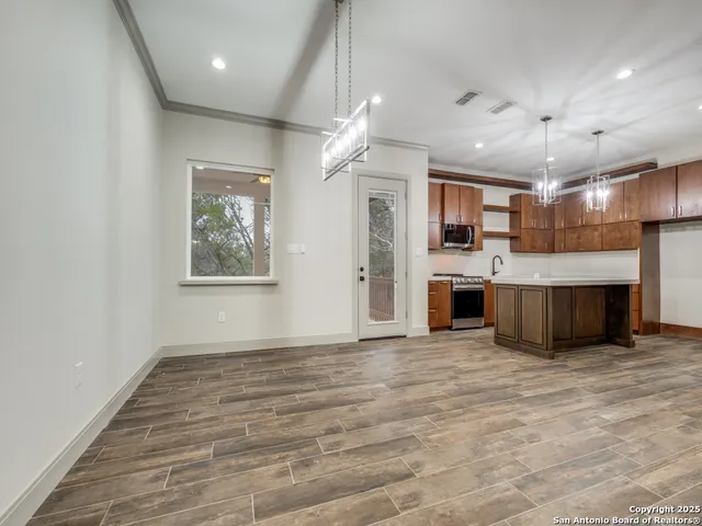 a view of a kitchen with a stove cabinets a ceiling fan and wooden floor