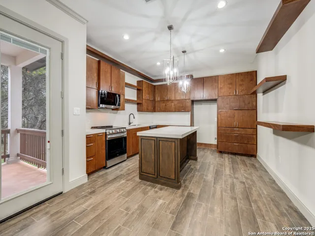 a large kitchen with a large counter top a sink stainless steel appliances and cabinets