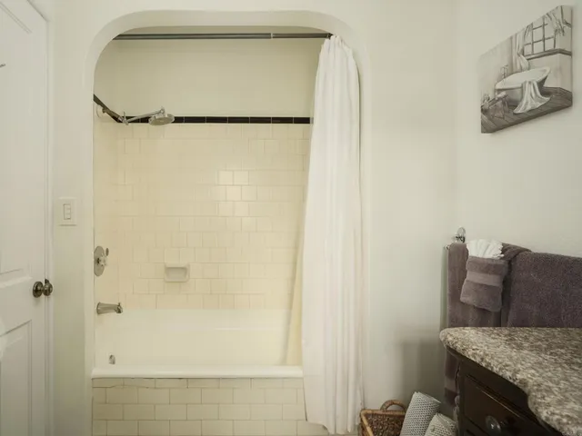 a bathroom with a granite countertop shower and a mirror