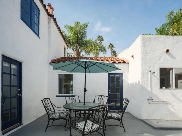 a patio with a table and chairs and potted plants
