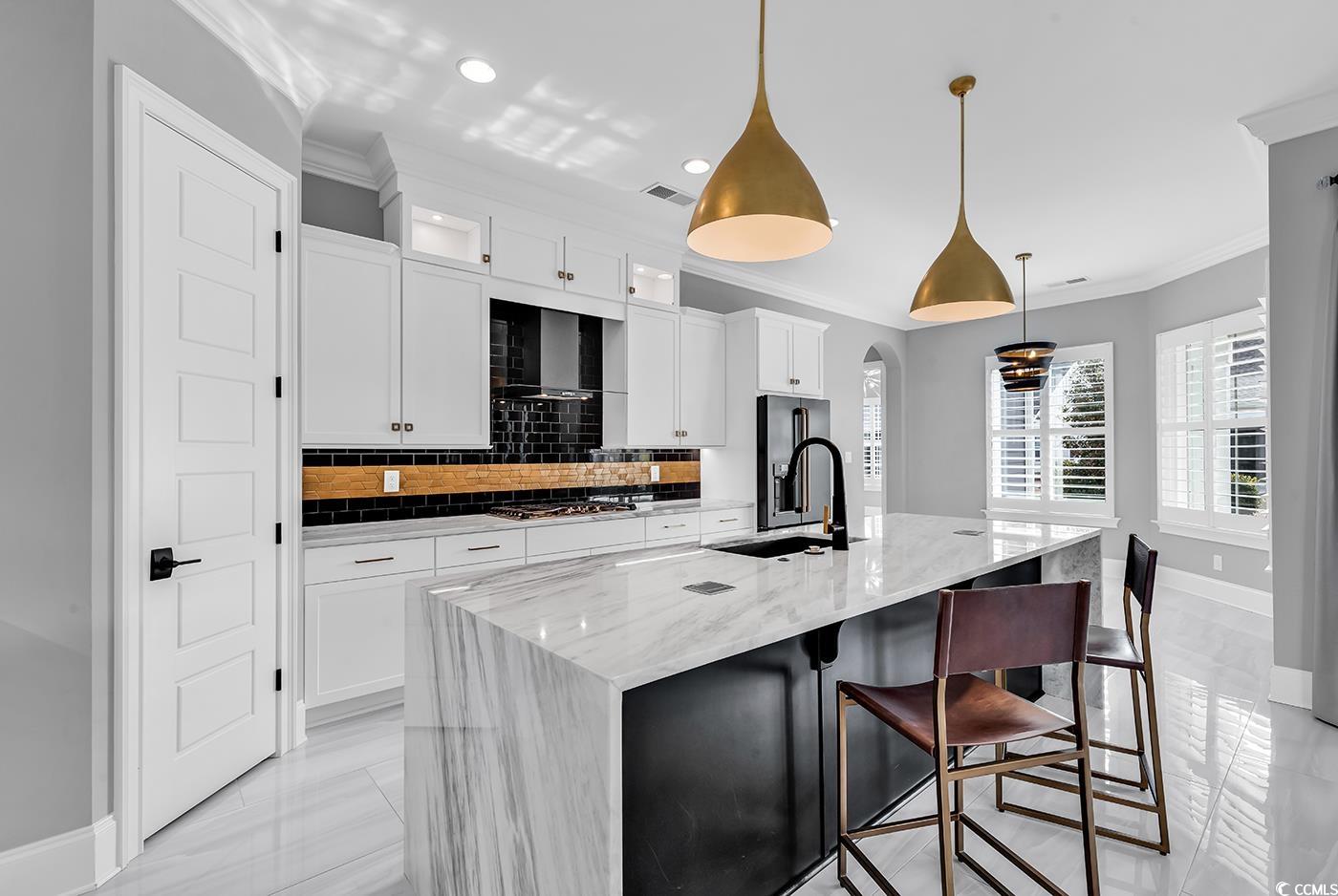 5960 Bolsena Place Myrtle Beach, SC 29572 - Photo 12 of 40 Kitchen featuring a spacious island, sink, white cabinetry, light stone counters, and pendant lighting