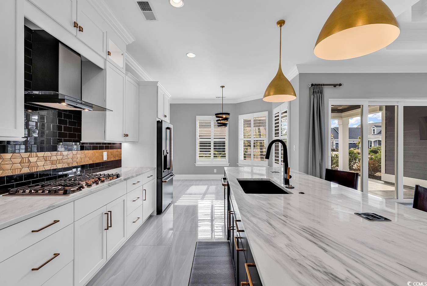 5960 Bolsena Place Myrtle Beach, SC 29572 - Photo 13 of 40 Kitchen featuring white cabinetry, sink, stainless steel gas cooktop, light stone counters, and high end fridge