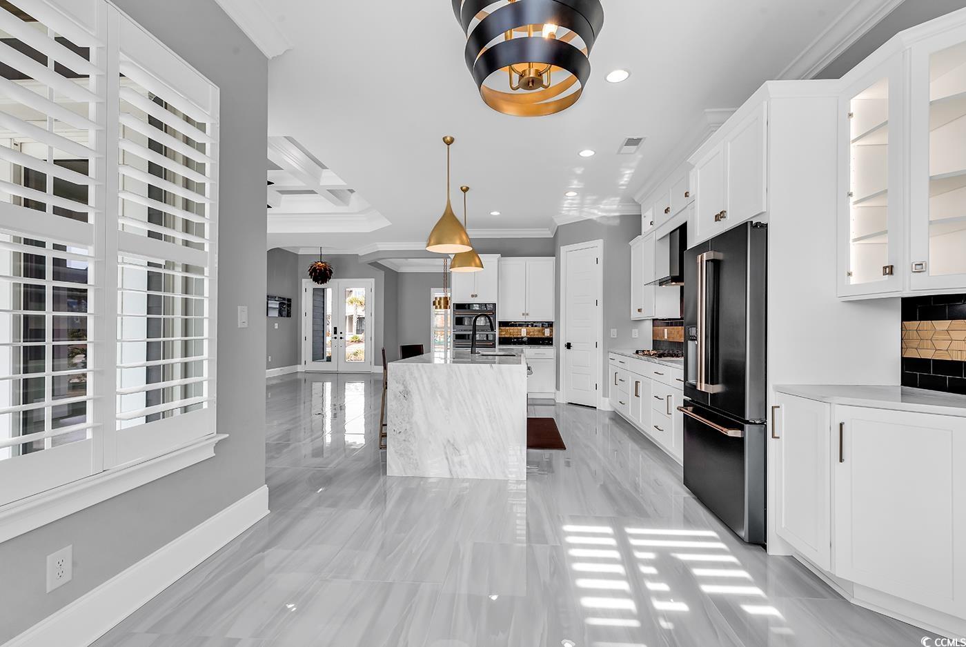 5960 Bolsena Place Myrtle Beach, SC 29572 - Photo 16 of 40 Kitchen with decorative light fixtures, an island with sink, high end refrigerator, white cabinets, and crown molding