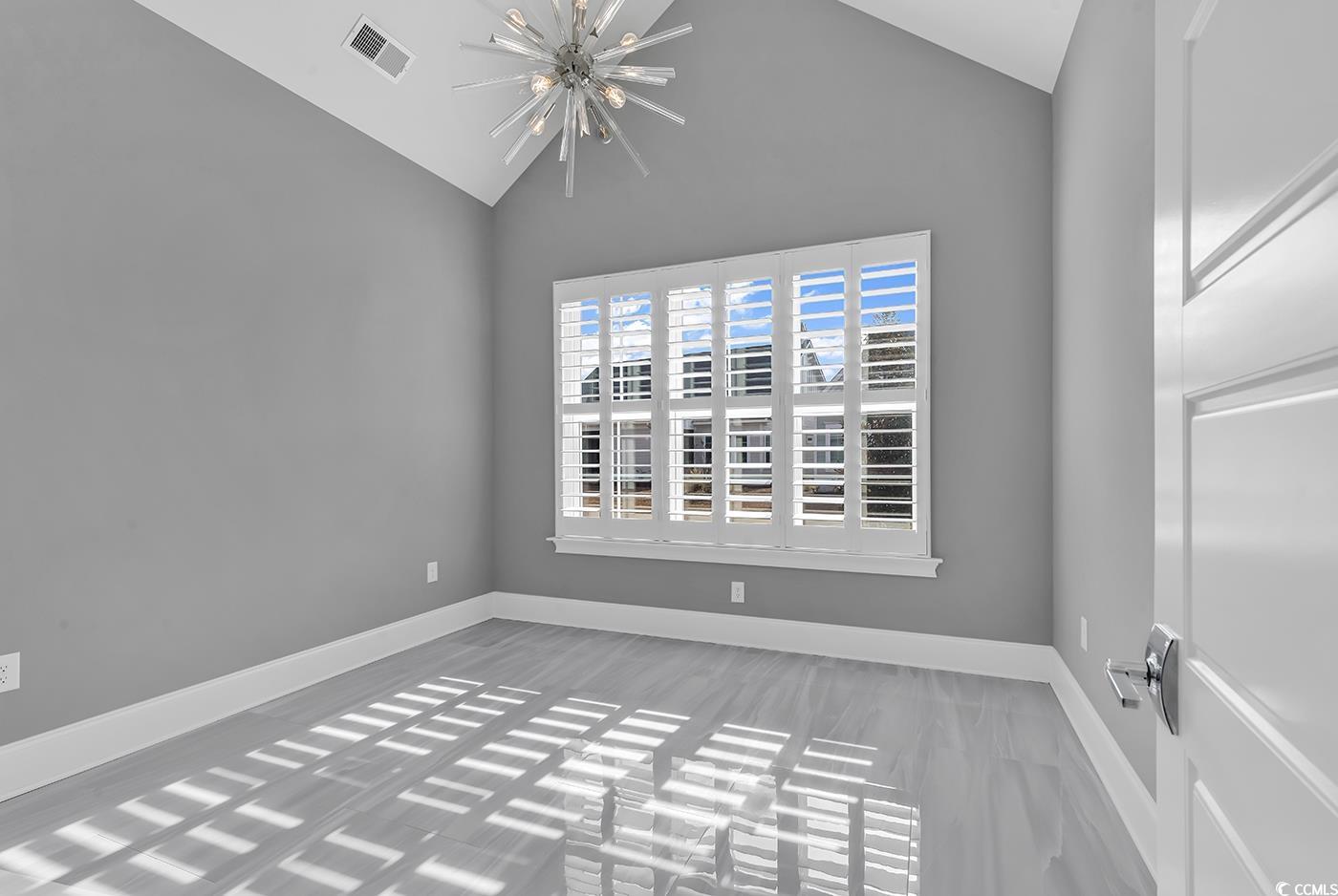 5960 Bolsena Place Myrtle Beach, SC 29572 - Photo 18 of 40 Empty room featuring vaulted ceiling and a chandelier
