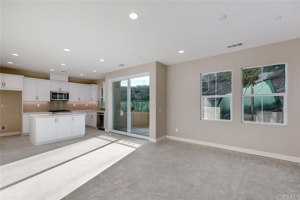 a large white kitchen with kitchen island a stove a sink a refrigerator and a counter top space