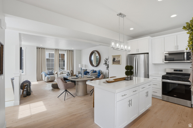7338 South Seven Tree Lane, Unit 75 Midvale, UT 84047 - Photo 29 of 30 Kitchen with open floor plan, stainless steel appliances, white cabinetry, decorative light fixtures, and light wood-style floors
