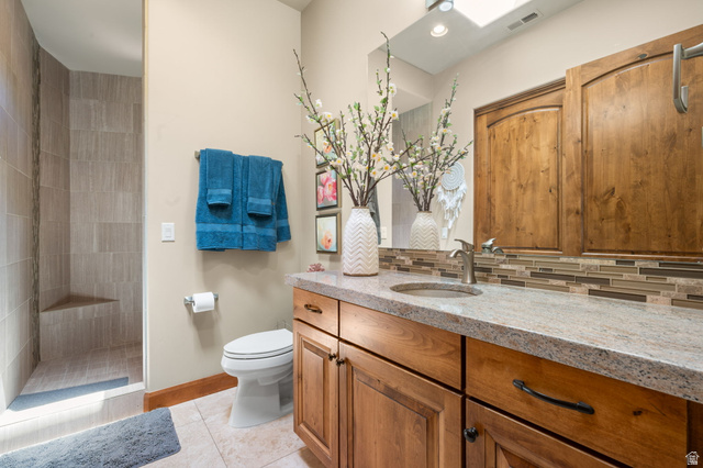 2331 West Entrada Trail, Unit 61 St. George, UT 84770 - Photo 21 of 69 Tiled shower with built-in bench, natural wood-finish vanity with ample storage, integrated sink, and granite-style countertop