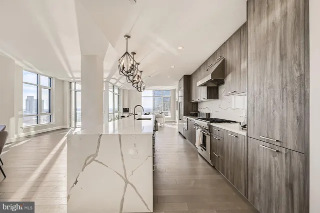 a kitchen with stainless steel appliances granite countertop a refrigerator a oven a stove and white cabinets with wooden floor