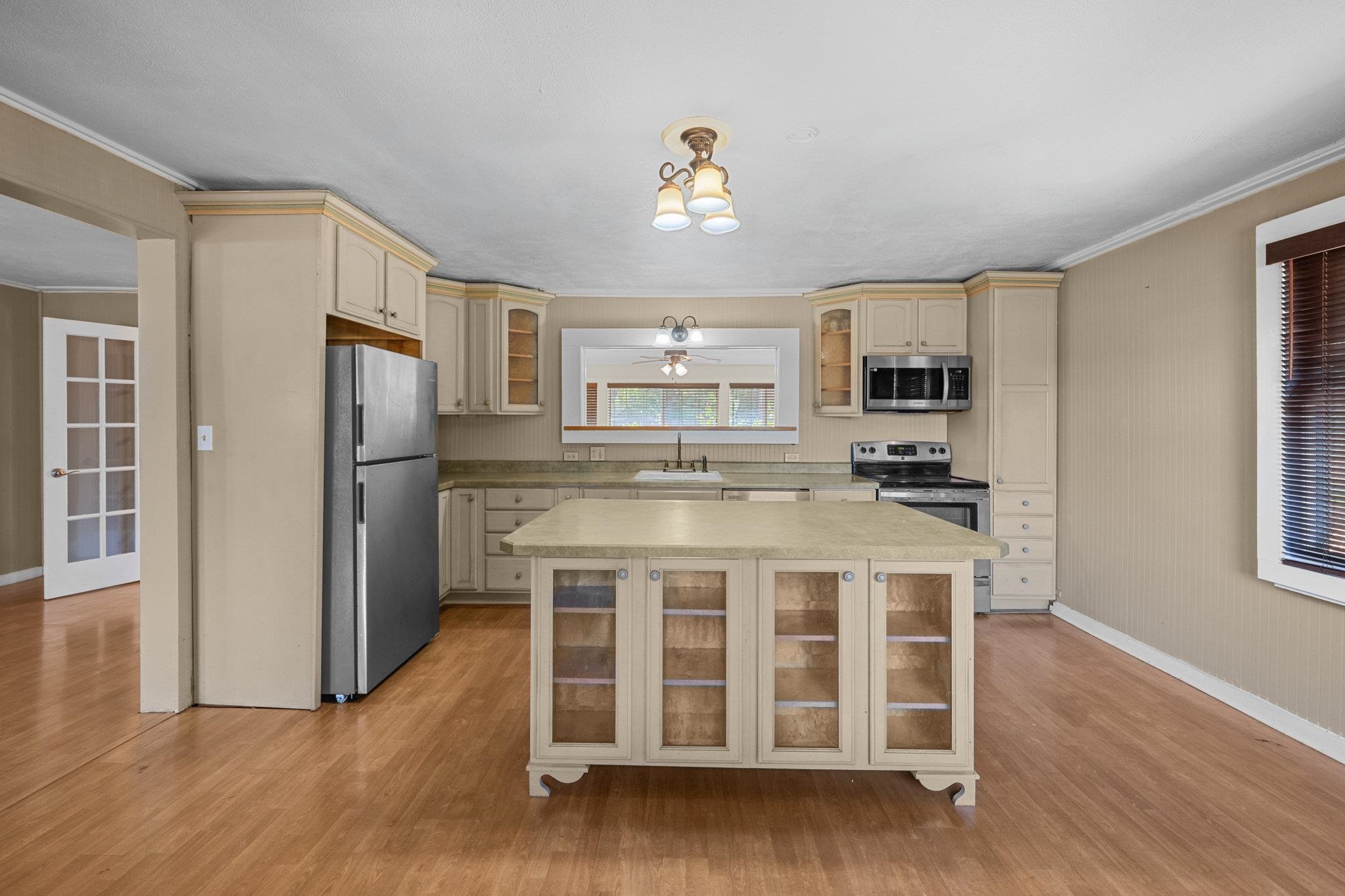 815 Kuulei Street Haiku, HI 96708 - Photo 3 of 26 a kitchen with stainless steel appliances kitchen island granite countertop a refrigerator a stove a sink dishwasher and white cabinets with wooden floor