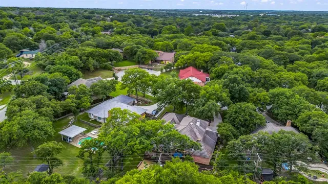an aerial view of residential house with outdoor space and trees all around